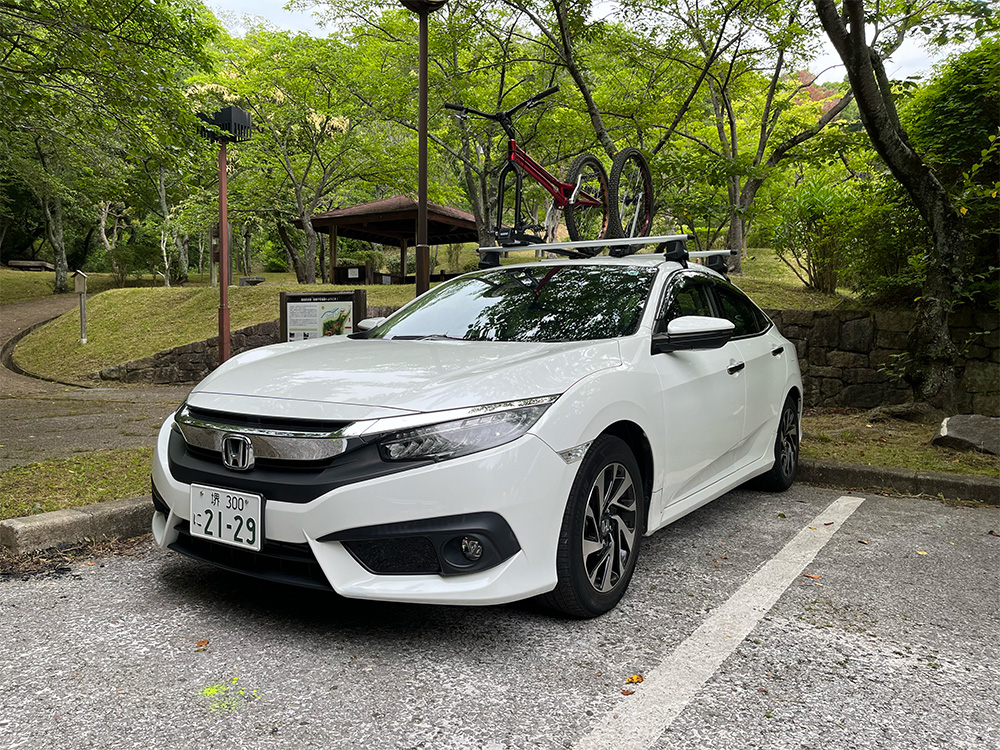 シビックセダンにルーフキャリアを取り付け、サイクルアタッチメントをつけて自転車を積載してる写真
